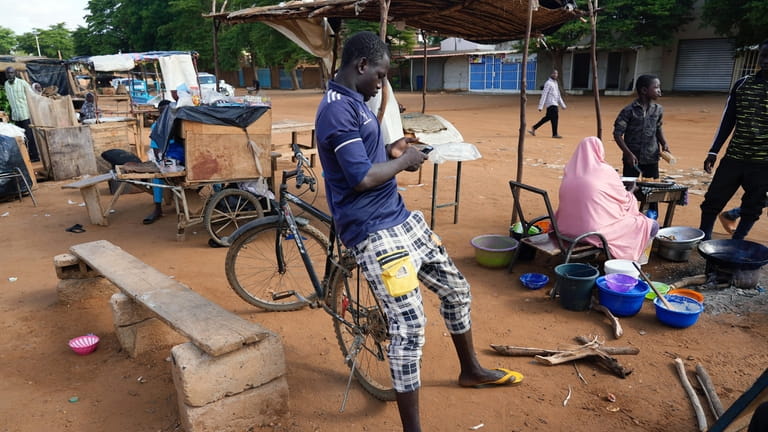 A man checks his phone in Niamey, Niger, Friday, Aug....