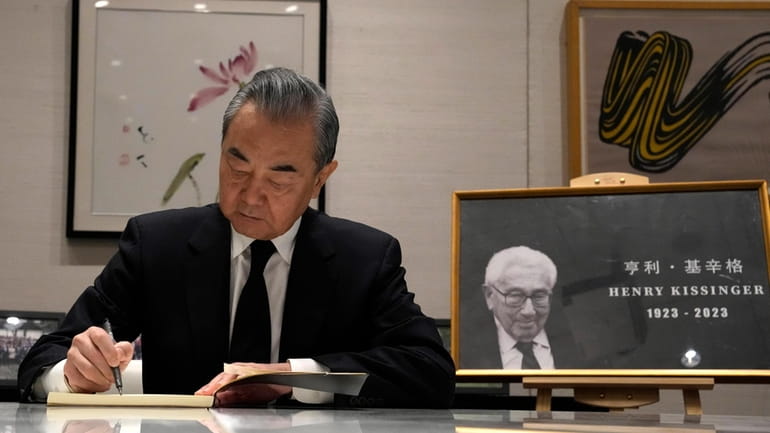 Chinese Foreign Minister Wang Yi signs a condolence book for...