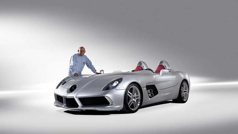 Sterling Moss stands next to a Mercedes-Benz SLR. One might...