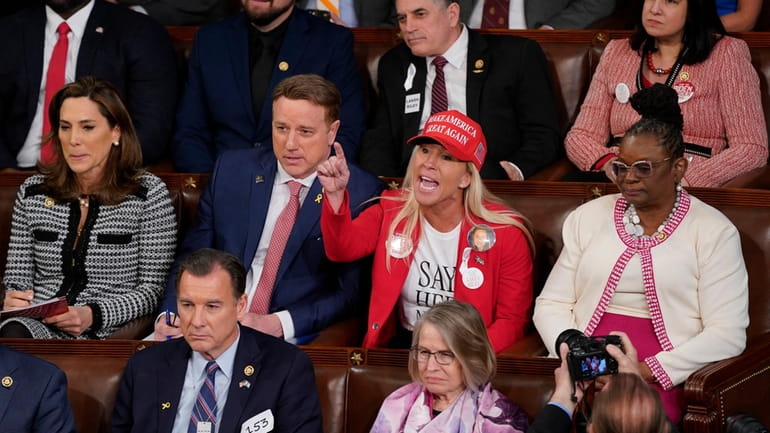 Rep. Marjorie Taylor Greene, wearing her MAGA hat, seated behind...