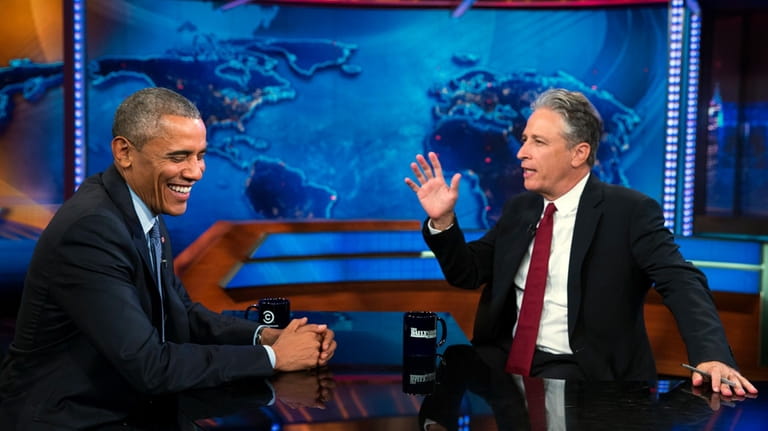 President Barack Obama, left, talks with Jon Stewart, host of...