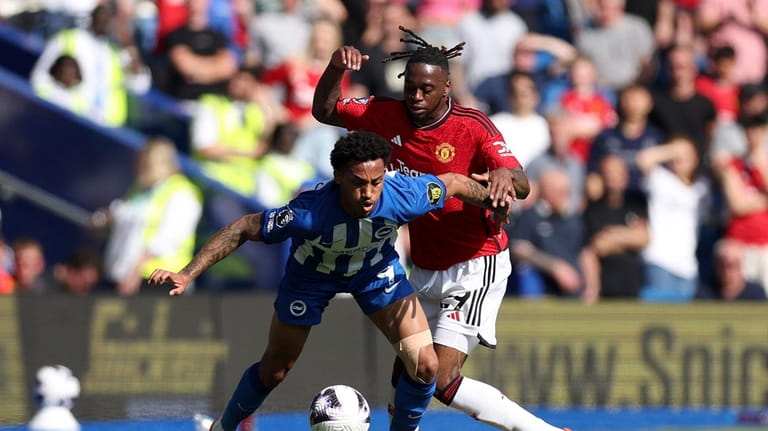 Brighton's Joao Pedro, left and Manchester United's Aaron Wan-Bissaka viefor...