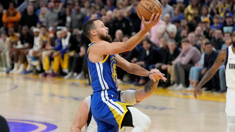 Golden State Warriors guard Stephen Curry, foreground, shoots against Dallas...