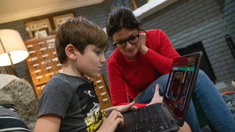 Izzy King plays learning games on his computer as his mom,...