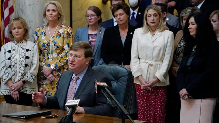 Mississippi Republican Gov. Tate Reeves is surrounded by legislative supporters...
