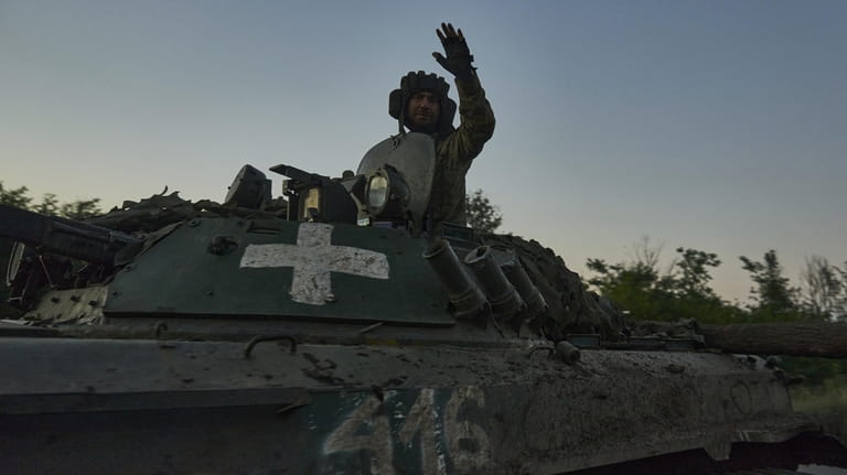 A Ukrainian soldier waves atop an APC at the front...