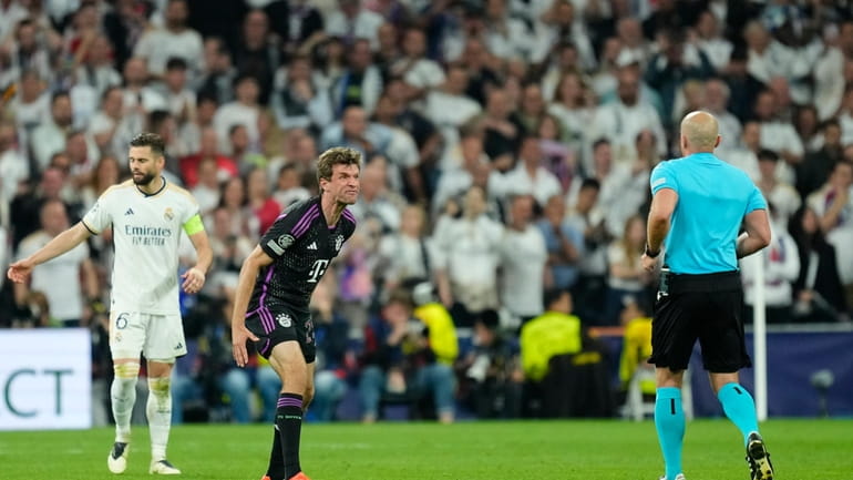 Bayern's Thomas Mueller, centre, reacts with referee during the Champions...