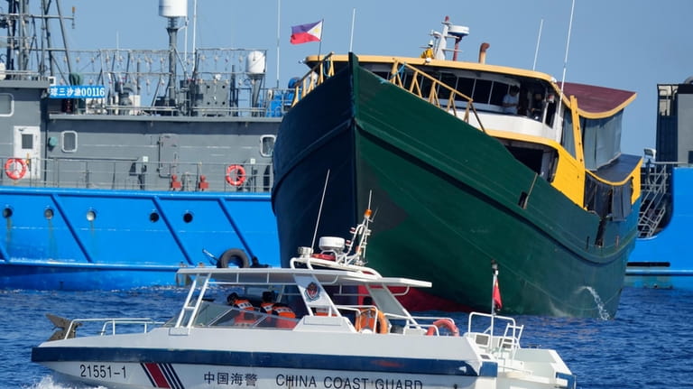 A Chinese coast guard boat moves near the Philippine resupply...