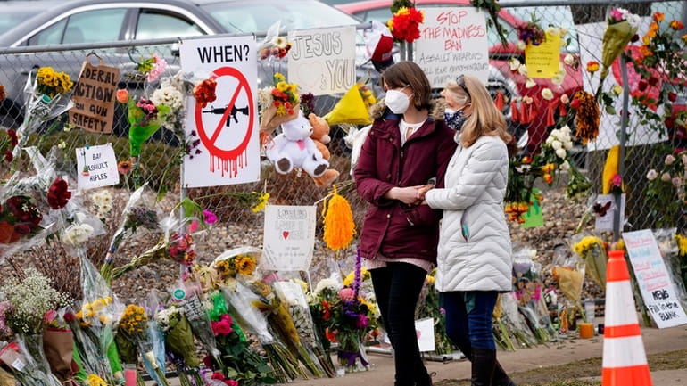 Mourners walk along the temporary fence put up around the...