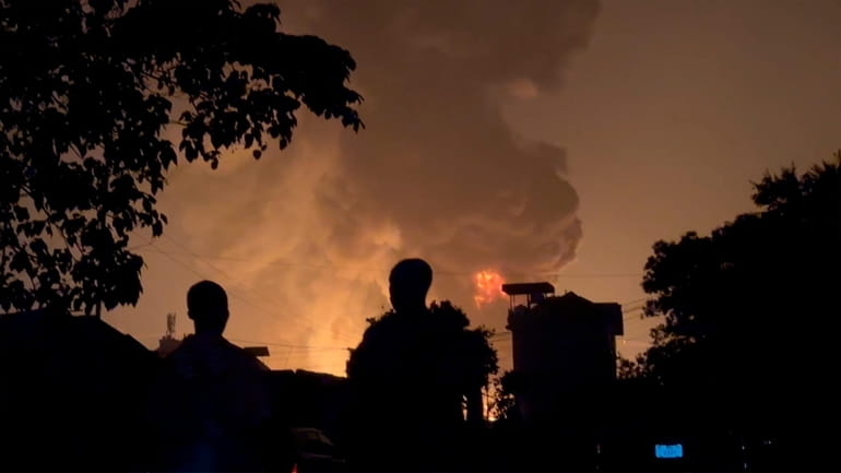 In this image made from video, residents watch a plume...