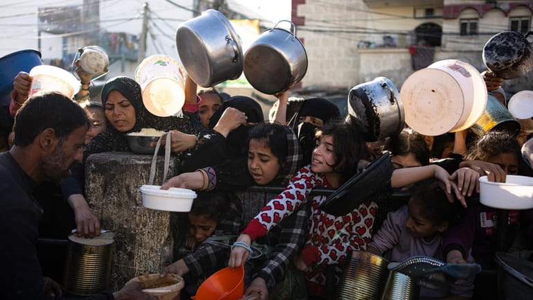 Palestinians line up for a free meal in Rafah, Gaza...