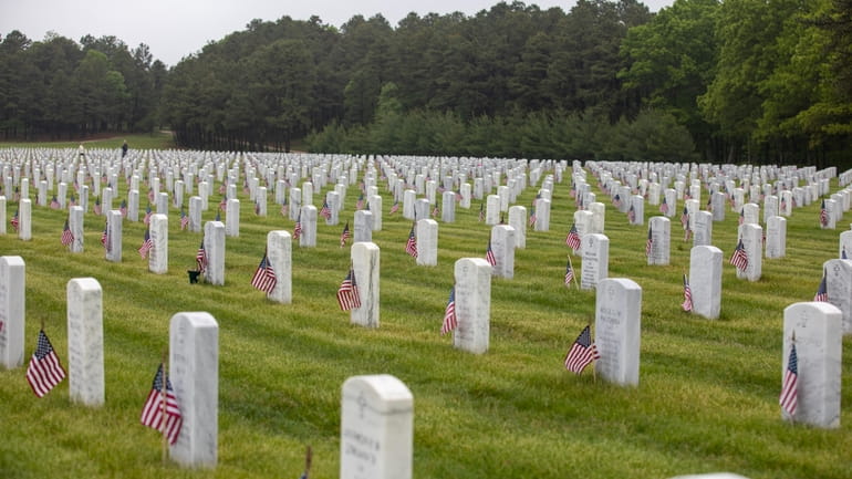 Veteran headstones are marked with American flags at Calverton National...