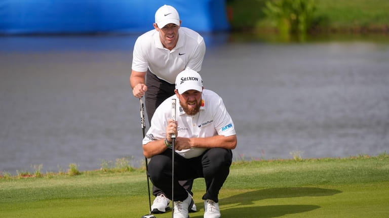 Rory McIlroy, of Northern Ireland, standing, and his teammate Shane...
