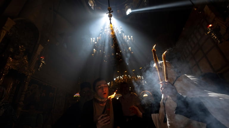 Christian pilgrims hold candles as they gather during the ceremony...