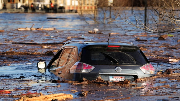 A car floats in a flooded parking lot at the...