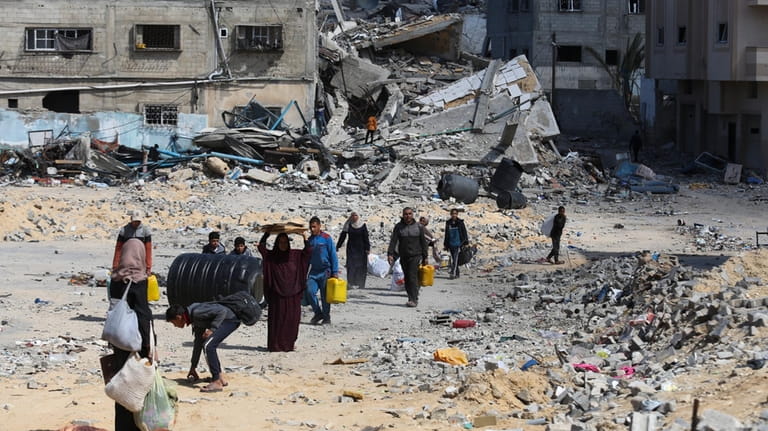 Palestinians walk through the destruction left by the Israeli offensive...
