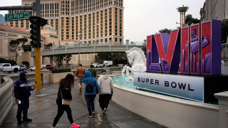 People walk by signage for the Super Bowl at Caesars...