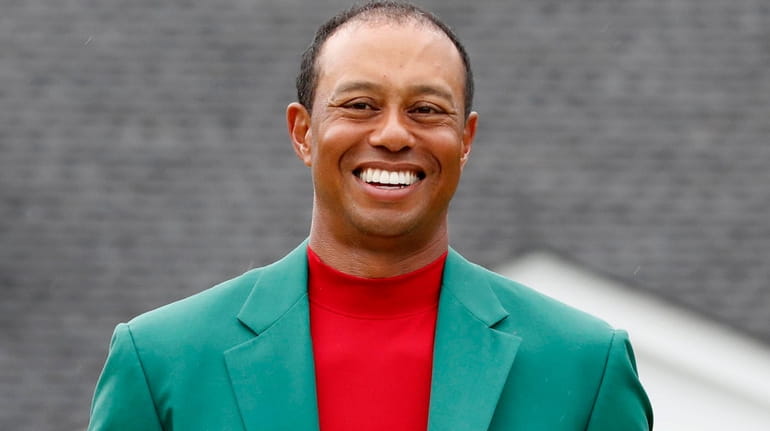 Tiger Woods poses with the Masters trophy and green jacket...