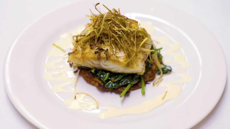 Pan roasted stripped bass, topped with slivered scallions, sits on...