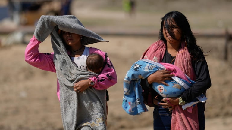 Women carry babies after arriving by boat from La Bulla...