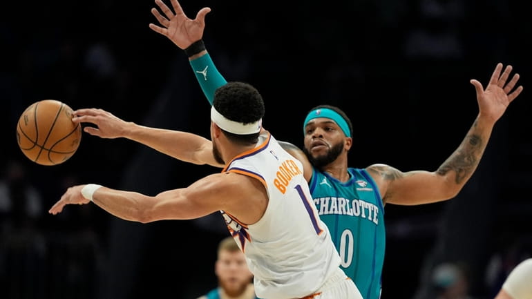 Phoenix Suns guard Devin Booker passes around Charlotte Hornets forward...