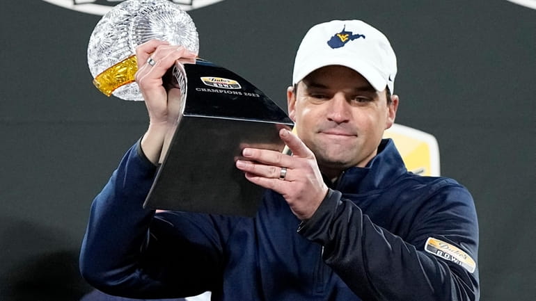 West Virginia head coach Neal Brown gets holds the trophy...