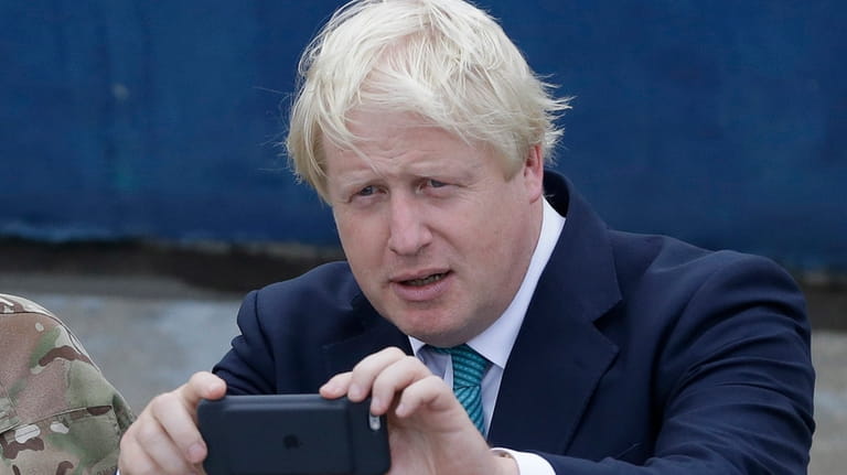 British Foreign Secretary Boris Johnson, right, takes a photo of...