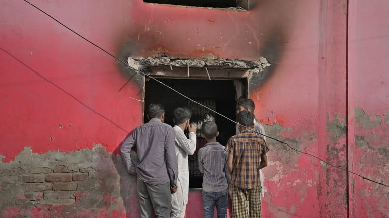 Youngsters look at a church vandalized by angry Muslim mob...