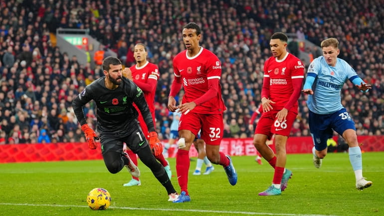 Liverpool's goalkeeper Alisson, left, goes for the ball as teammates...