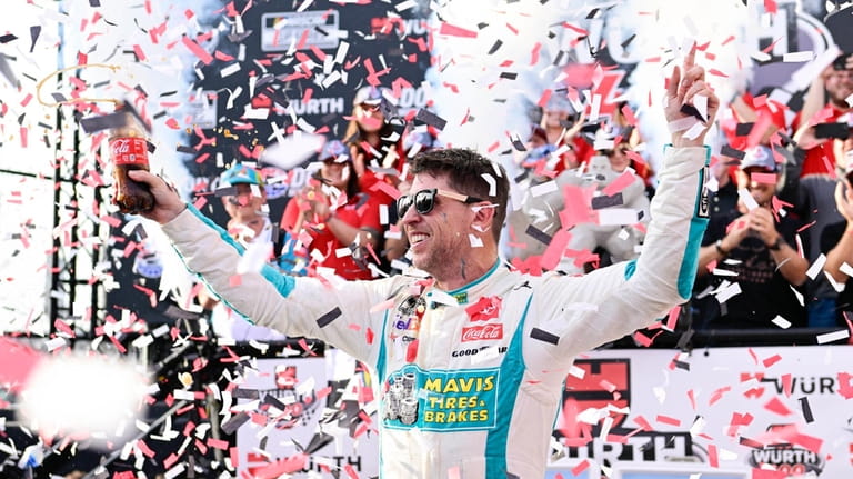 Denny Hamlin celebrates in Victory Lane after winning a NASCAR...