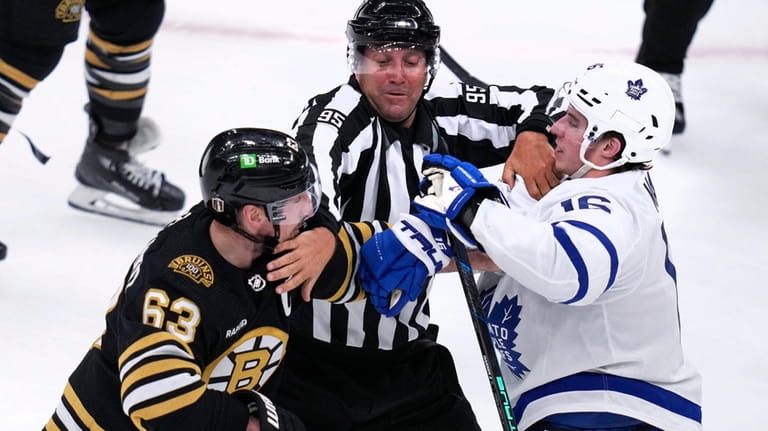 NHL linesman Jonny Murray, center, tries to separate Boston Bruins...