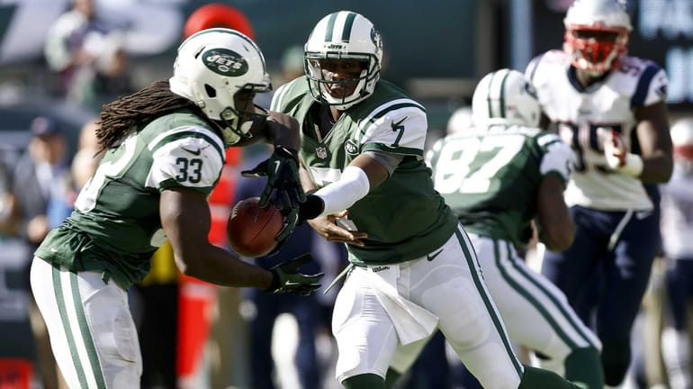 Geno Smith (no. 7) hands the ball off to Chris...