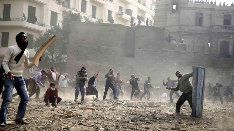 Egyptian anti government protesters throw stones during clashes in downtown...