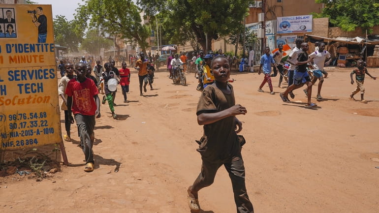 Children run in the streets of Niamey, Niger, Sunday, Aug....