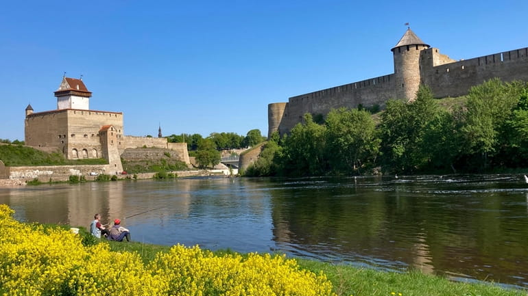 Men fish near the fortresses of Narva, left, in Estonia,...