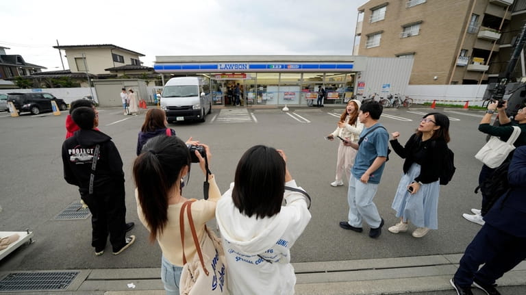 Tourists take pictures in front of the Lawson convenience store,...