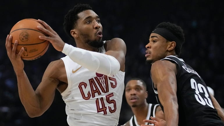 The Cavaliers' Donovan Mitchell, left, drives to the basket during...