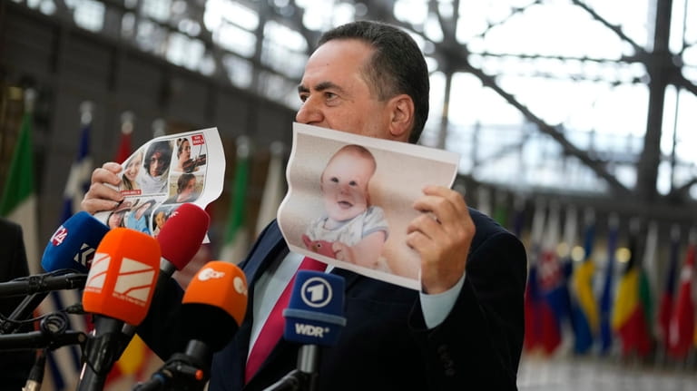 Israel's Foreign Minister Israel Katz holds up a paper photo...