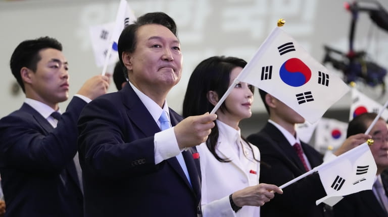 South Korean President Yoon Suk Yeol waves a Korean flag...