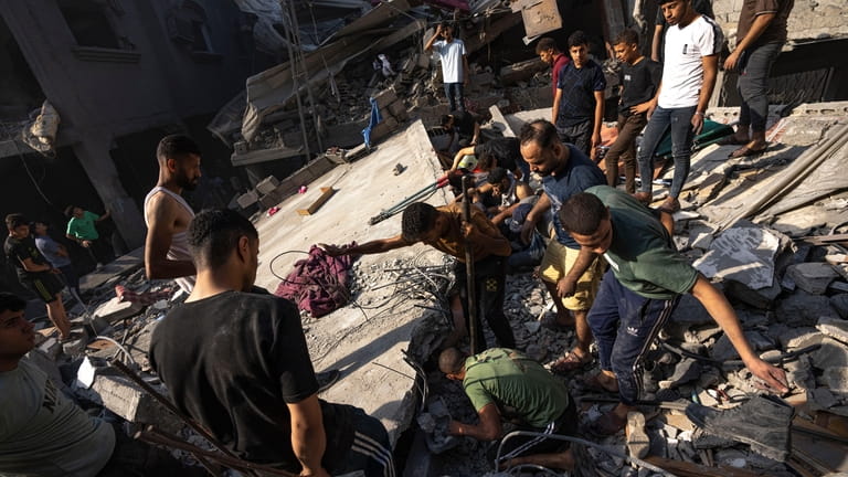 Palestinians search for bodies and survivors in the rubble of...
