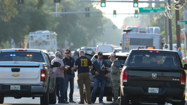 Law enforcement officials investigate the scene of a mass shooting...