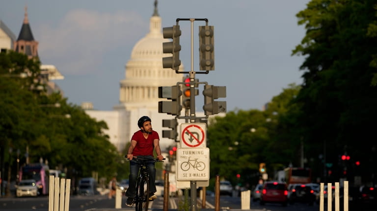 A cyclist rides up Pennsylvania Avenue with the U.S. Capitol...