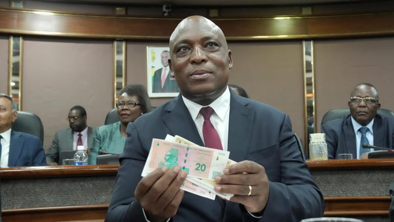 Reserve Bank of Zimbabwe Governor, John Mushayavanhu holds a sample...