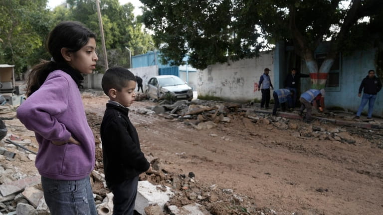 Children look at the site where three Palestinians were killed...