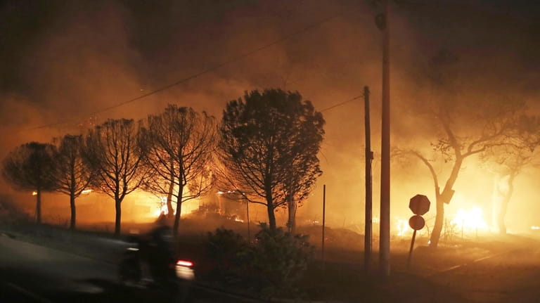 Buildings burn in the town of Mati, east of Athens,...