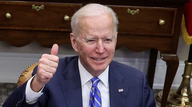 President Joe Biden gives a thumbs up as he speaks...