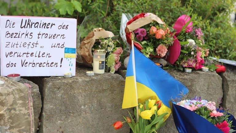 Flowers and a small Ukrainian flag are laid at a...