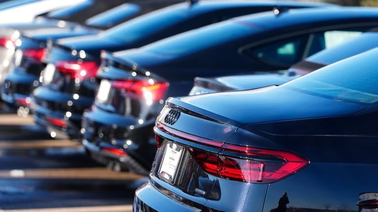 Unsold 2023 sedans sit in a long row at an...