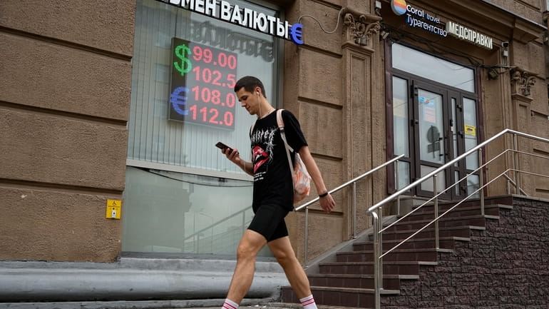 A man walks past a currency exchange office in Moscow,...