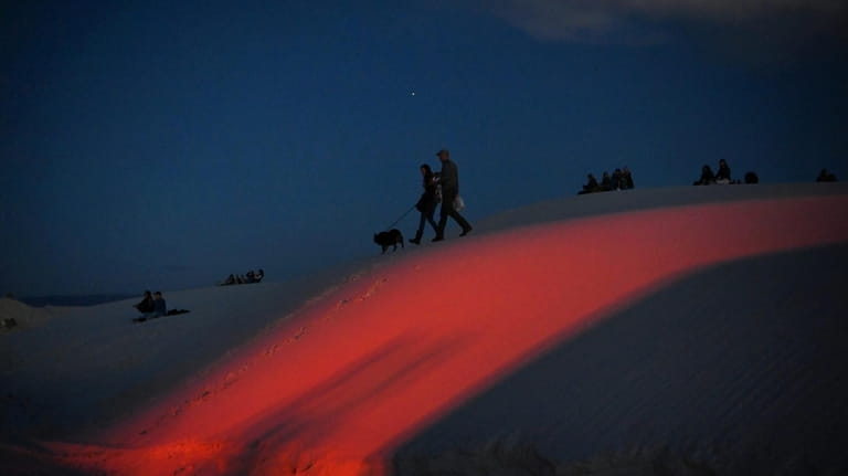 Visitors walk their dog in White Sands National Park. 